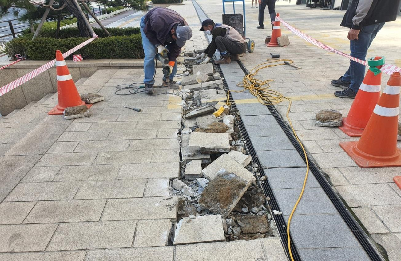 인천의 보도블록 보수 현장. 파손된 대형 고압 블록을 뿌레카로 파쇄하여 제거하고 있음.